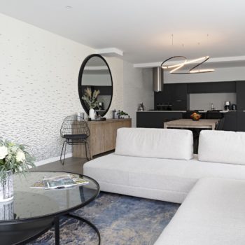 Décoration et agencement d'une maison sur plans à Bédée - salon banquettes en angle, tables gigognes noir et tapis bleu et beige Décoration et agencement d'une maison sur plans à Bédée - salon banquettes en angle, tables gigognes noir et tapis bleu et beige