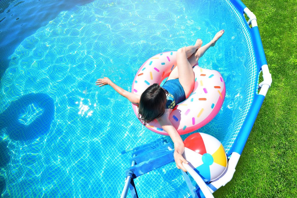 Pool time. Girl has fun in a summer metal frame pool.